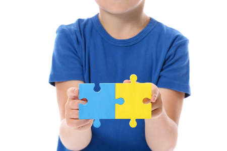 Little boy with autistic disorder and with puzzle pieces on white backgroundの写真素材