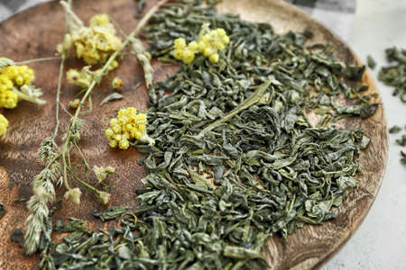Dry green tea with herbs on wooden plateの写真素材