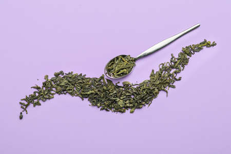 Dry green tea with spoon on color backgroundの写真素材