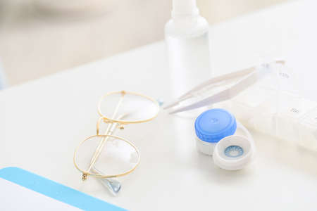 Container with contact lenses, tweezers and glasses on tableの写真素材