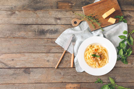 Plate of tasty pasta with chicken on wooden tableの写真素材