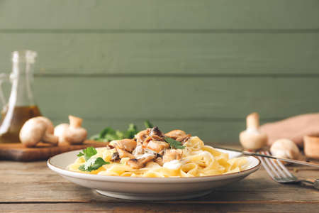 Plate of tasty pasta with chicken and mushrooms on wooden tableの写真素材