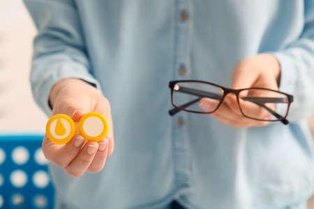 Woman holding glasses and contact lens case in clinic