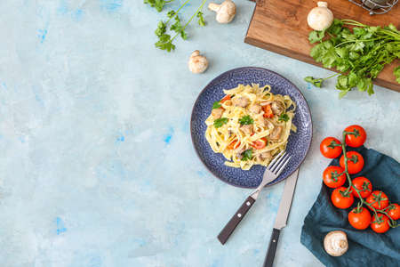 Plate of tasty pasta with chicken and cherry tomatoes on color tableの写真素材
