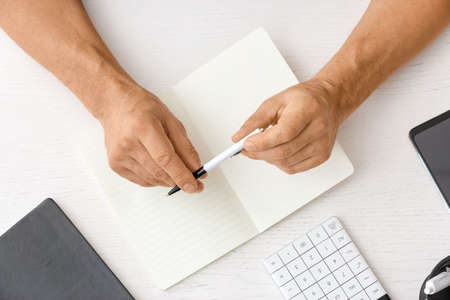 Man writing in notebook with pen