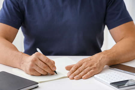 Man writing in notebook with pen