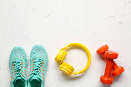 Sportive shoes, dumbbells and headphones on light backgroundの写真素材