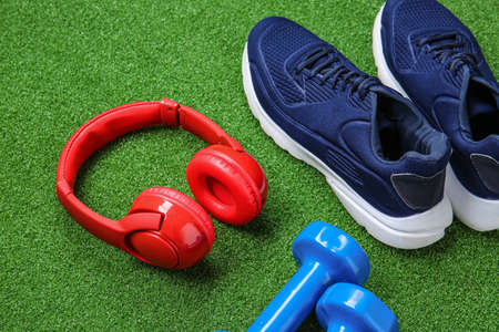 Sportive shoes, dumbbells and headphones on color backgroundの写真素材