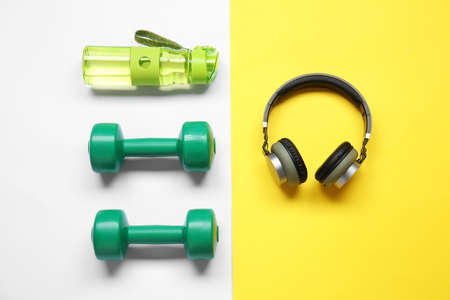 Bottle of water, dumbbells and headphones on color backgroundの写真素材