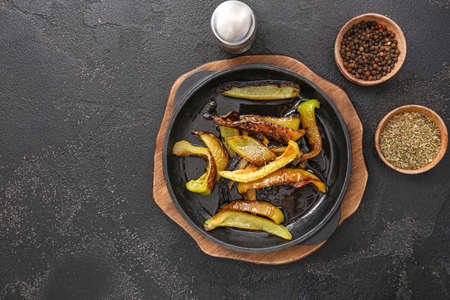 Roasted bell peppers with spices in pan on dark tableの写真素材