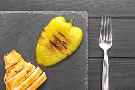 Composition with tasty grilled pepper and chicken on dark plateの写真素材