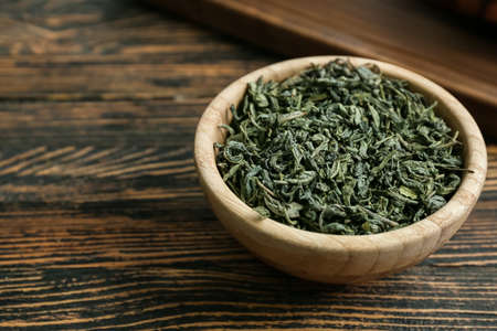 Bowl with dry green tea on wooden tableの写真素材