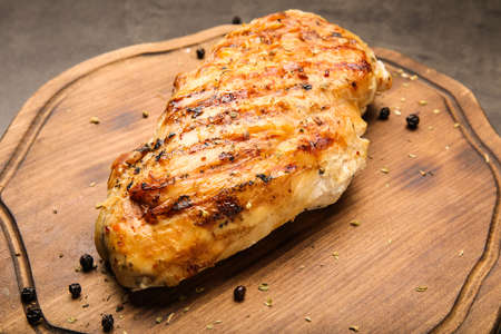 Board with cooked chicken fillet on dark backgroundの写真素材