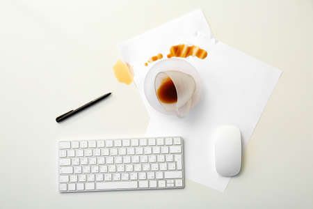PC accessories, overturned cup and spilled coffee on tableの写真素材