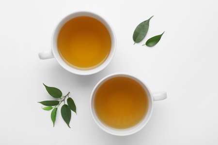 Two cups of tea and green leaves on white backgroundの写真素材