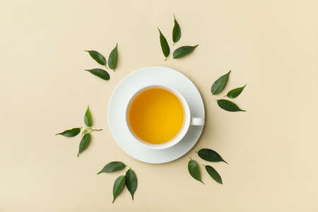 Cup of tea and green tea leaves on light backgroundの写真素材