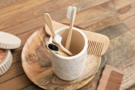 Cup with toothbrushes and hair combs on wooden tableの写真素材