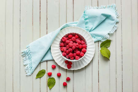 Bowl with ripe raspberries on table