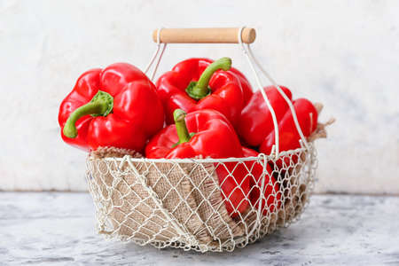 Red bell pepper in wicker basket on tableの写真素材