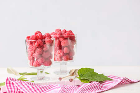 Glasses with tasty ripe raspberries on table