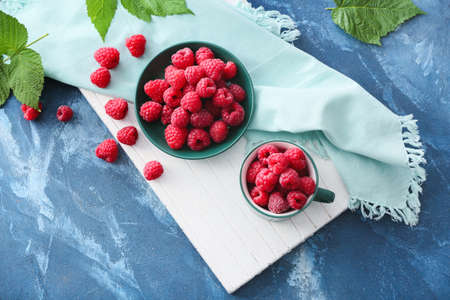 Plate with tasty ripe raspberries on color background