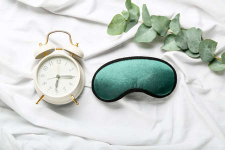 Sleep mask and alarm clock on light backgroundの写真素材