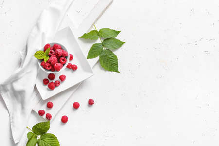 Bowl with ripe raspberries on white background