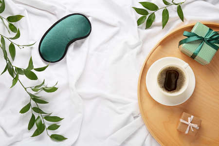 Sleep mask and tray with cup of coffee on light backgroundの写真素材