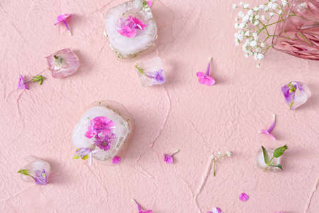 Beautiful flowers frozen in ice on color background