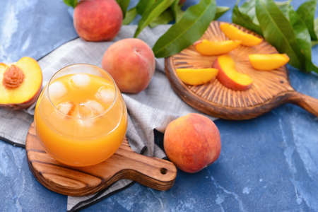 Glass of tasty peach juice on color backgroundの写真素材