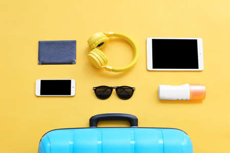 Packed suitcase with beach accessories and devices on color background. Travel conceptの写真素材
