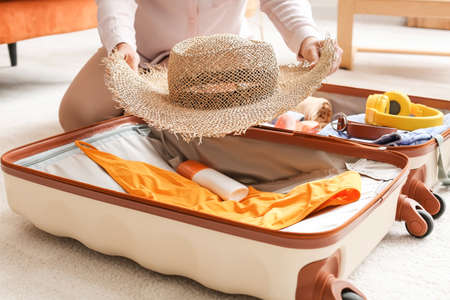 Woman packing suitcase at home. Travel concept