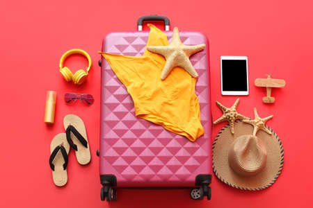 Packed suitcase with beach accessories on color background. Travel conceptの写真素材