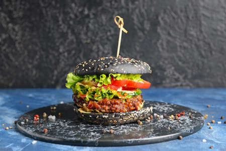 Tasty burger with black bun on tableの写真素材