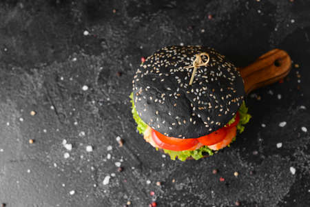 Tasty burger with black bun on dark backgroundの写真素材