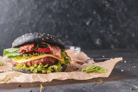 Tasty burger with black bun on dark backgroundの写真素材