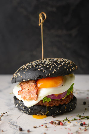 Tasty burger with black bun on tableの写真素材