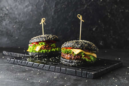 Tasty burgers with black bun on dark backgroundの写真素材