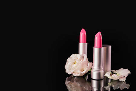 Beautiful lipsticks and flower on black background