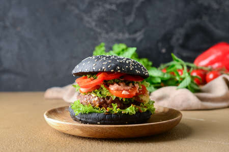 Tasty burger with black bun on tableの写真素材