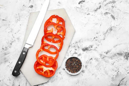 Sliced red bell pepper and knife on light background
