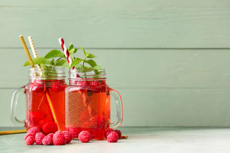 Mason jars of cold raspberry tea on table