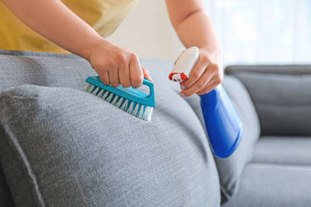 Woman removing dirt from sofa at homeの写真素材