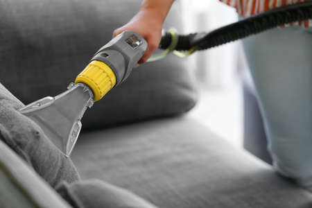 Woman removing dirt from sofa at homeの写真素材