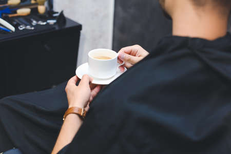 Handsome man with cup of coffee in barbershopの写真素材