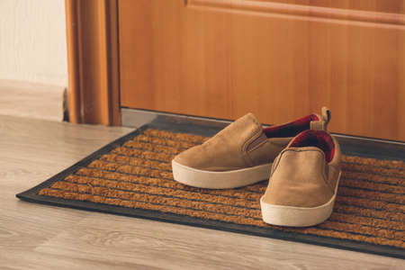Little boy shoes near door on matの写真素材