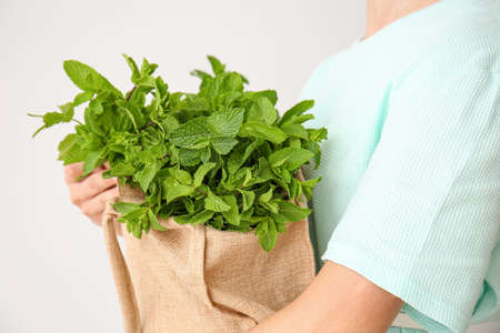 Young woman with bag of fresh mint on white backgroundの写真素材