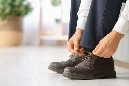 Young man putting on stylish shoes