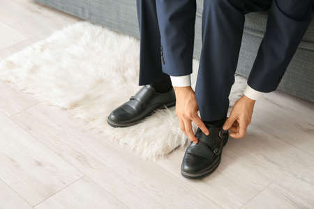 Young man putting on stylish shoesの写真素材