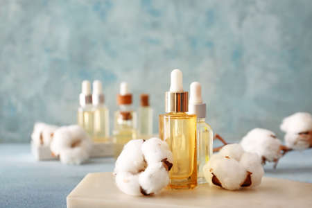 Composition with cosmetic oil and cotton flowers on tableの写真素材